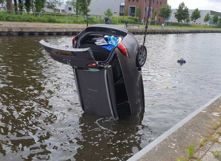 Auto rolt van kade het water van de Arkervaart in Nijkerk in