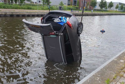 Auto rolt van kade het water van de Arkervaart in Nijkerk in